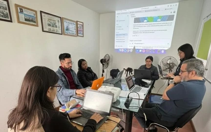 Grupo de docentes trabajando con portátiles alrededor de una mesa durante una capacitación.