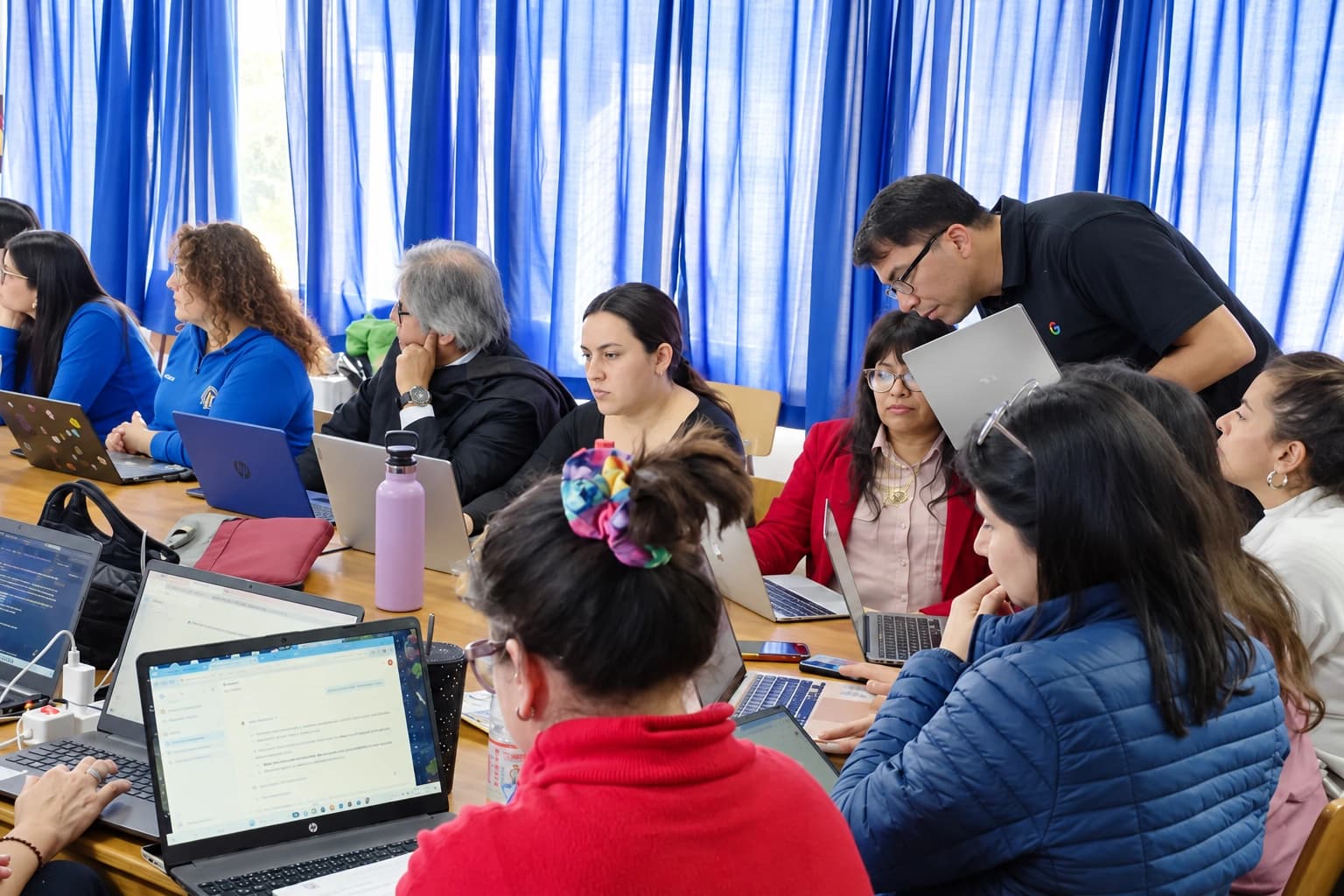 Docentes trabajando con portátiles junto a un formador de Educinnova durante un taller.