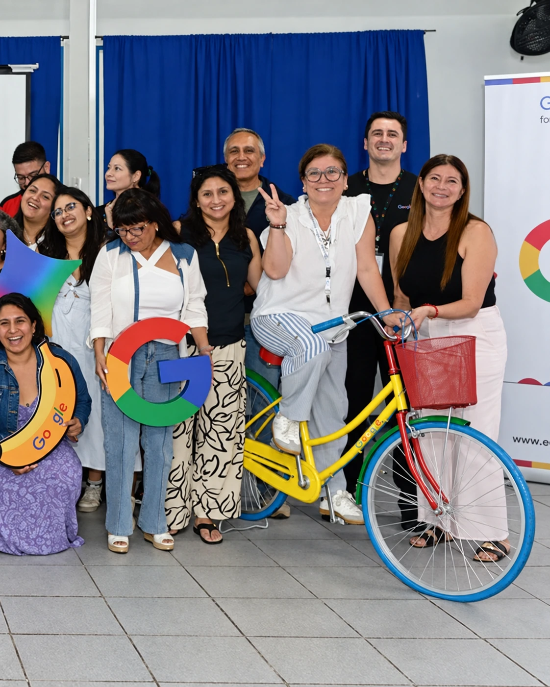 Docentes junto a la bicicleta de colores y el pendón de Google for Education durante una jornada educativa.